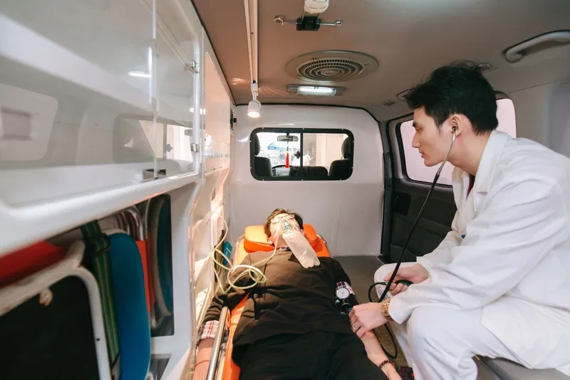 Người bị co giật nằm trên sàn, có người hỗ trợ sơ cứu bên cạnh